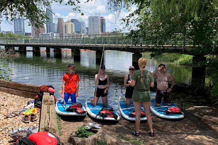 a group of people sitting on a bench next to a river