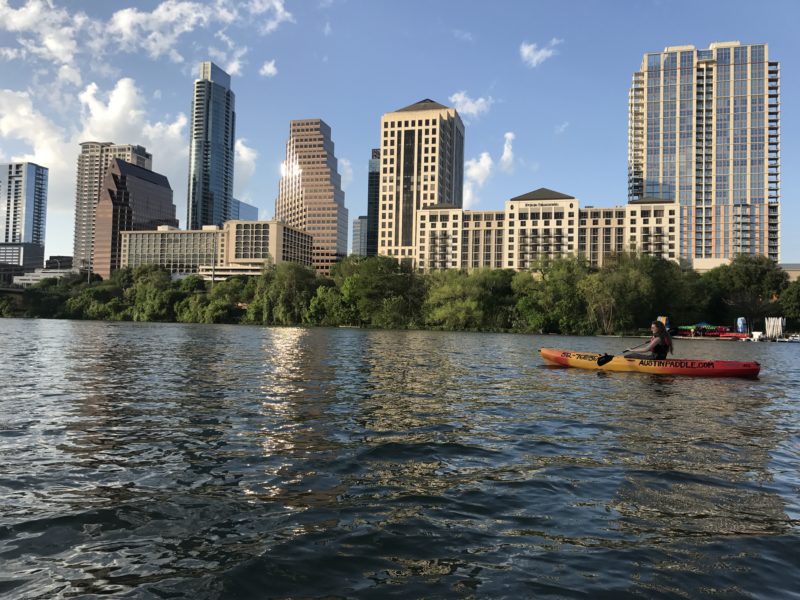 person kayaking with austin skyline in background